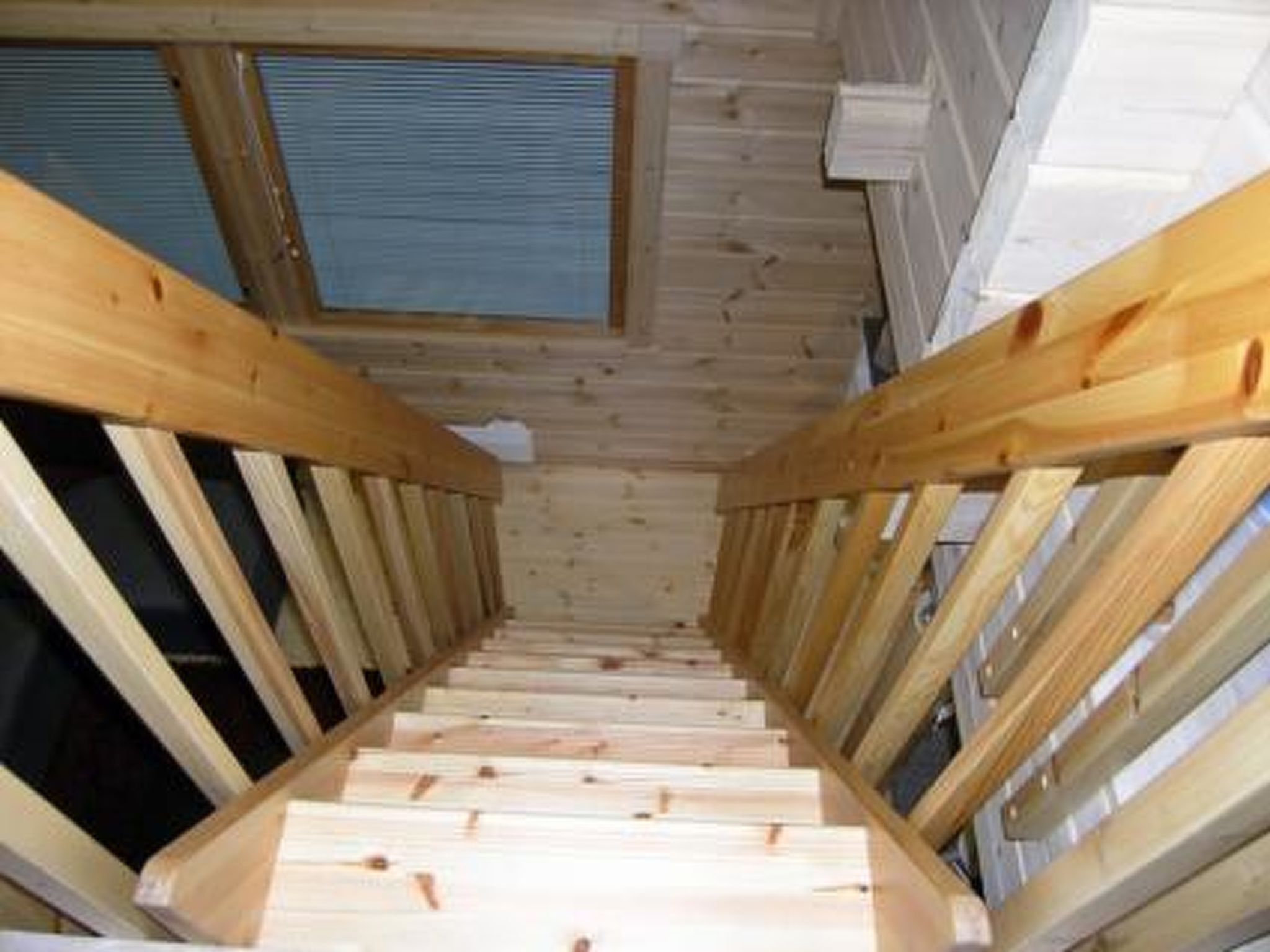Een houten trap met uitzicht op de lucht door een raam.