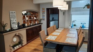 A dining area with a wooden table, wicker chairs, and a kitchen in the background. - Spacious vacation home with covered patio and sun terrace (Middelkerke)