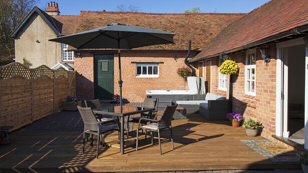 A patio with a table and chairs, a wooden fence, and a brick building with a green door. - West Mead Cottage (Wirral)