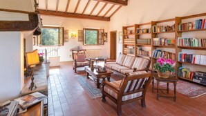 Un salon chaleureux avec une cheminée, des étagères en bois et des fauteuils confortables.