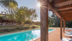 Une piscine agrémentée d’une pergola en bois et de chaises longues.