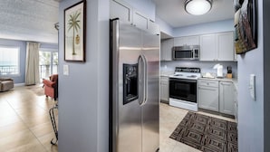 A modern kitchen with stainless steel appliances, grey cabinets, and a patterned rug.