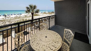 A balcony with a view of the beach, featuring a table and chairs.