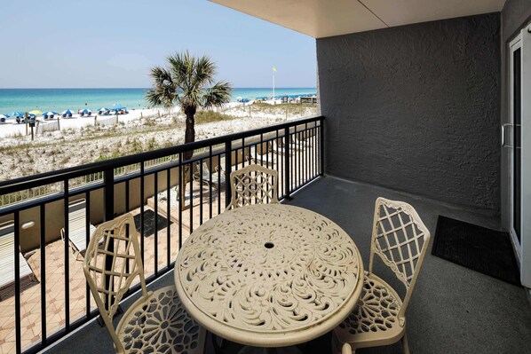 A balcony with a view of the beach, featuring a table and chairs.