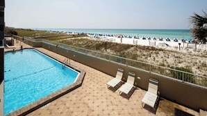 A pool with lounge chairs and a view of the beach.