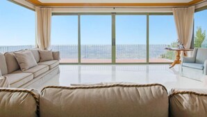 A spacious living room with a large balcony, a sofa, a chair, and a small table.