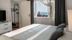Een slaapkamer met een bed, een televisie, een kledingkast en een raam met gordijnen.