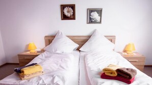 A double bed with white linens, two bedside tables with lamps, and two framed pictures on the wall. - Lachmöwe by Interhome (Norddeich)
