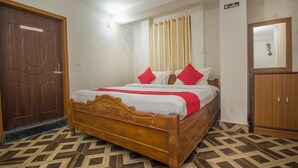 A bedroom with a wooden bed, a wardrobe, and a door. - Hotel Nirala (Darjeeling)