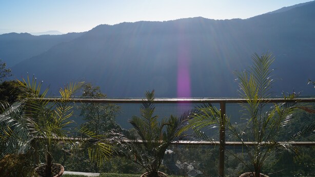 A view of a mountainous landscape with a clear sky and sunlight filtering through. - Hotel Nirala (Darjeeling)