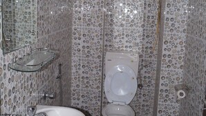 A bathroom with a toilet, sink, and shower. - Hotel Nirala (Darjeeling)