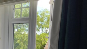 Una ventana con vistas a un paisaje verde y un edificio.