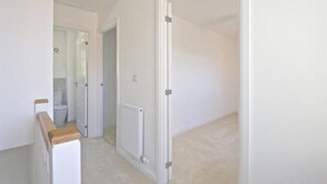Un pasillo con un radiador, un banco de madera y una puerta blanca.
