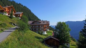 A mountain lodge with multiple wooden buildings, a road, and a view of the surrounding mountains. - Apartment Gloria by Interhome (Mürren)