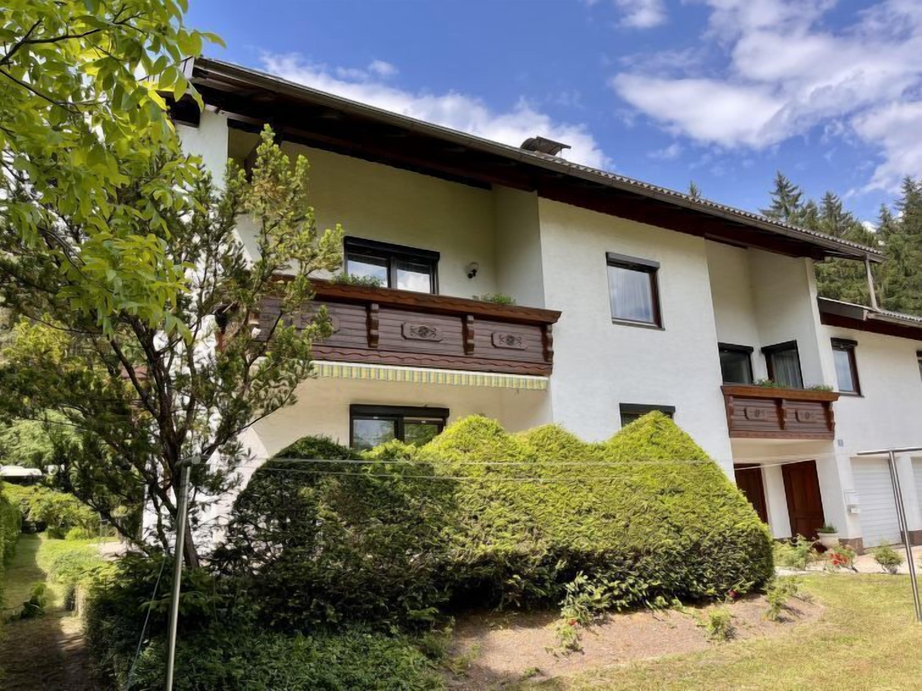 Un edificio di due piani con facciata chiara, numerose finestre e un balcone con ringhiera in legno.