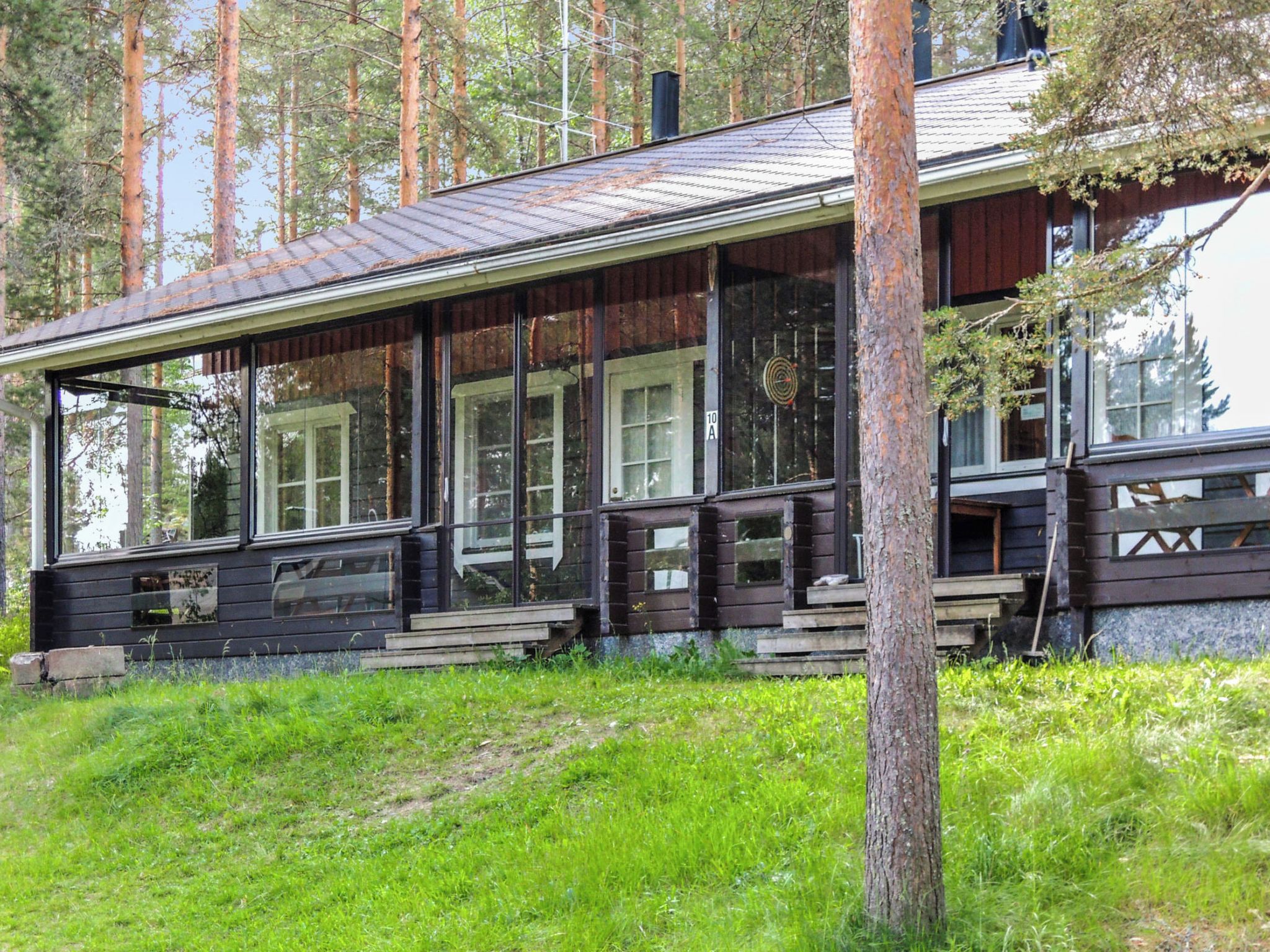 Eine Holzhütte mit großer Veranda, zahlreichen Fenstern und einem Metalldach.