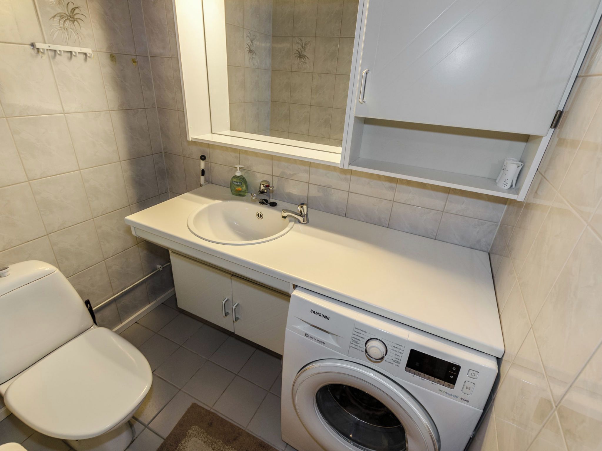 A bathroom with a toilet, sink, and washing machine.
