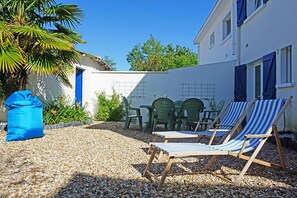 A patio area with a table and chairs, a blue bean bag, and a palm tree.