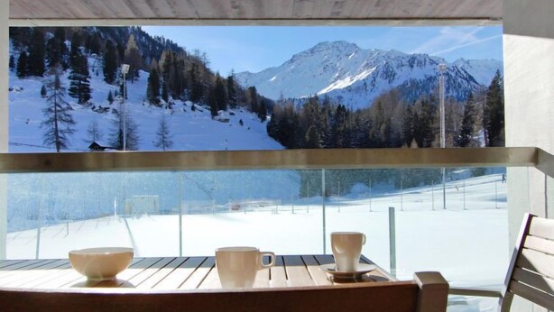 Een balkon met uitzicht op een besneeuwd berglandschap.