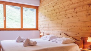 Een kamer met houten lambrisering, een bed, een nachtkastje en een raam.