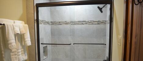 A walk-in shower with a glass door, a toilet, and a towel rack with towels.