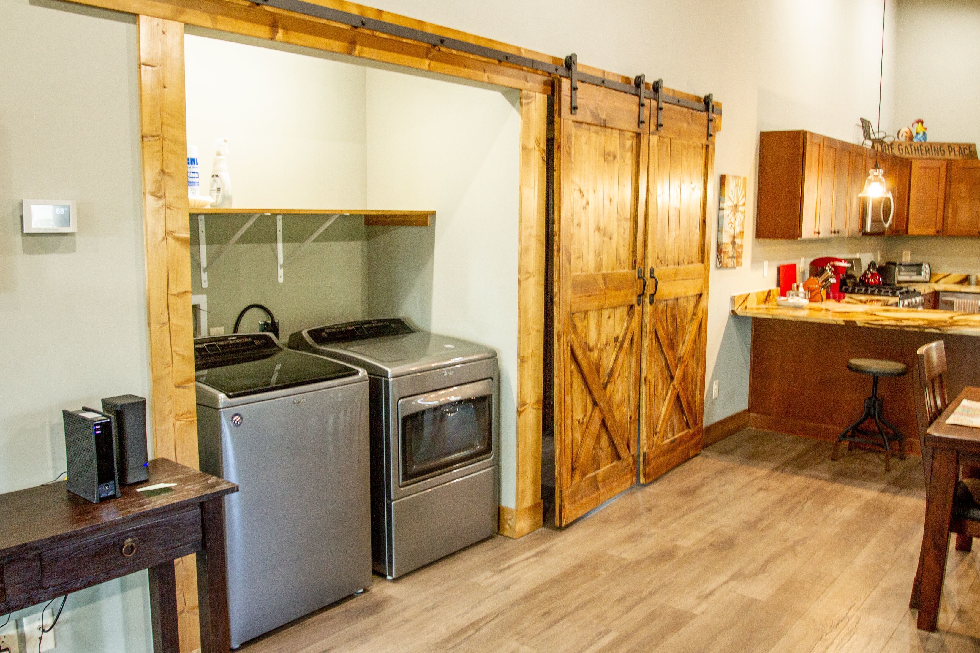 Una cocina con puerta corrediza de madera, electrodomésticos de acero inoxidable y una mesa de comedor de madera.