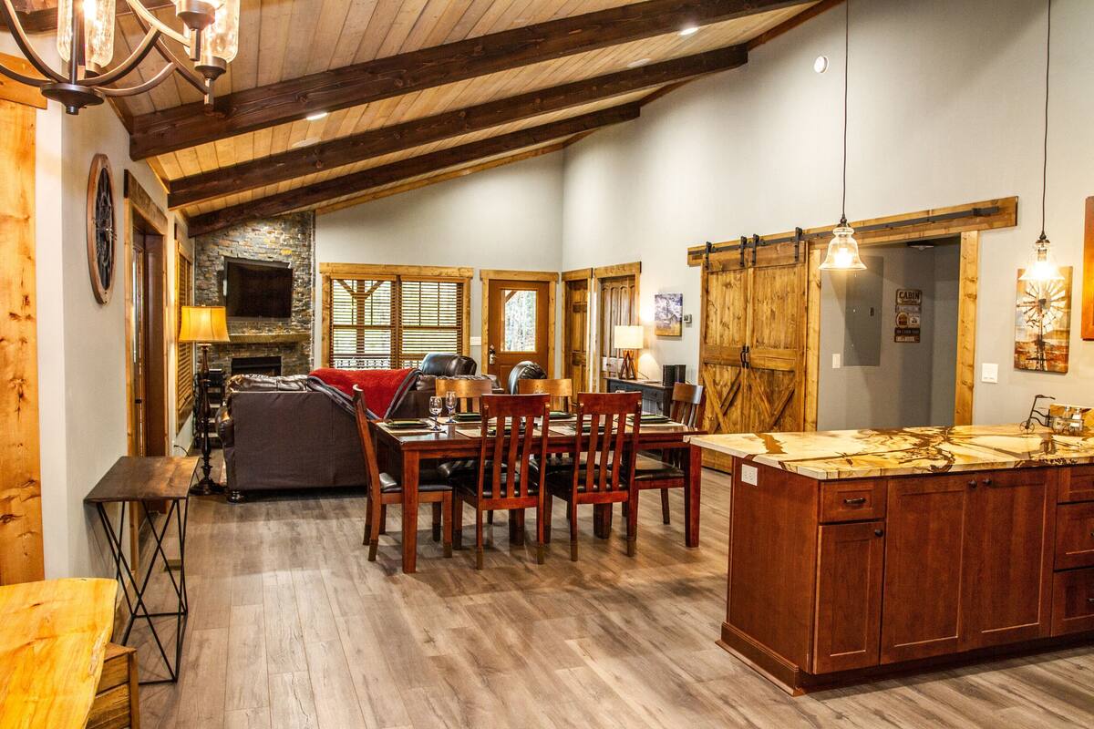 Una cocina amplia con armarios de madera, un comedor con mesa y sillas de madera, y una chimenea de piedra.