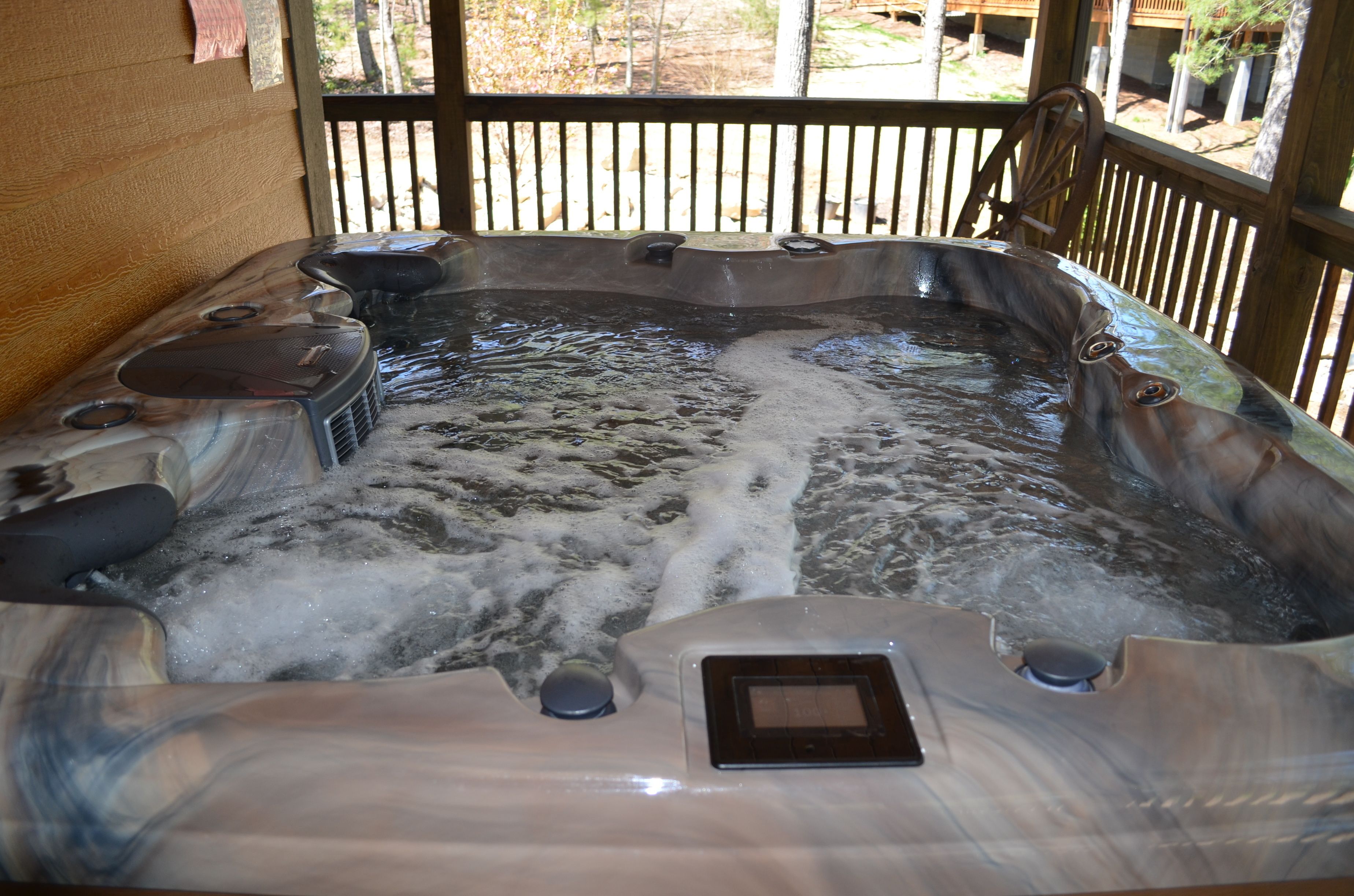 Un bain à remous doté de plusieurs jets, d’un panneau de commande et d’une terrasse en bois qui l’entoure.