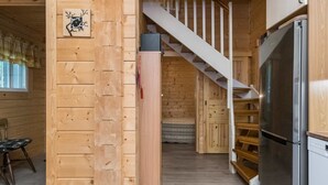 A wooden cabin interior with a kitchen, a dining area, and a staircase leading to an upper level. - Villa eerola by Interhome (Juva)