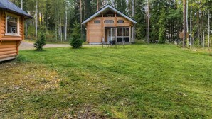 A wooden cabin with a large porch and a dining area, surrounded by a forest. - Villa eerola by Interhome (Juva)