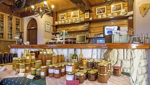 A rustic interior with wooden shelves displaying jars of preserves and a variety of glassware.