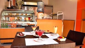 A dining area with a buffet counter, a water dispenser, and a dessert display. - Tababela Land (Tababela)