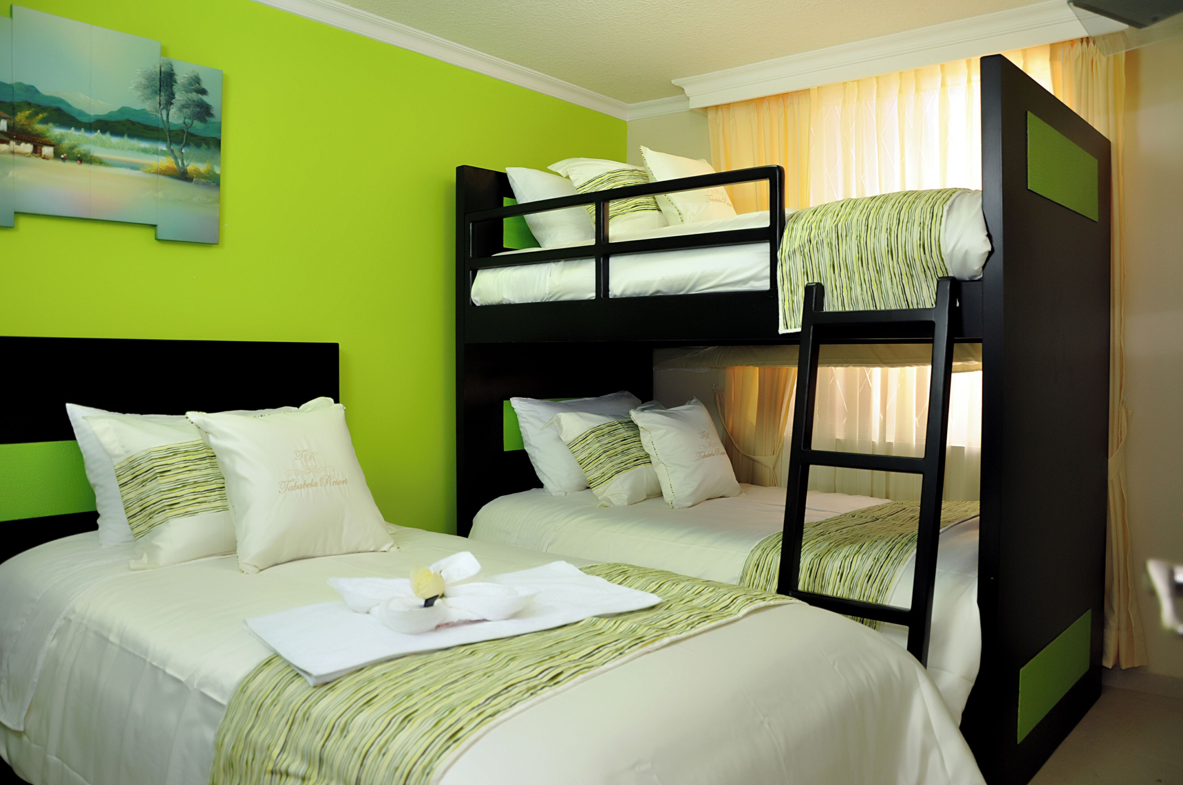 Una habitación de hotel con literas, una pared verde y un cuadro.
