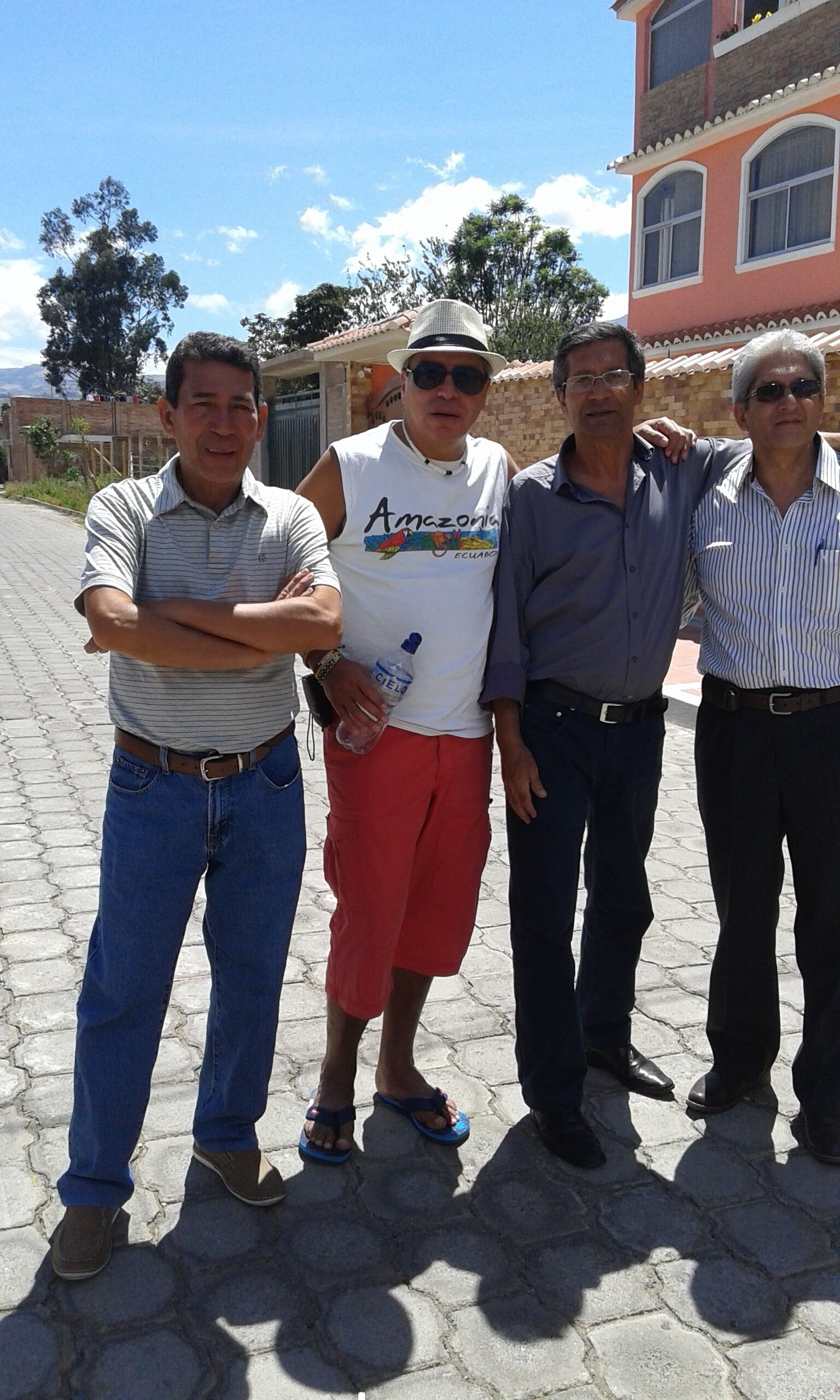 Un grupo de personas de pie en una zona pavimentada, con un edificio al fondo.