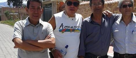Un grupo de personas de pie en una zona pavimentada, con un edificio al fondo.