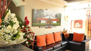 A living room with a sofa, a wall-mounted painting, and a floral arrangement. - Tababela Land (Tababela)