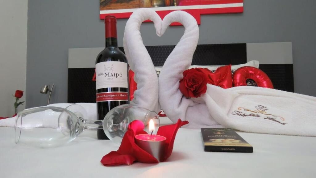 Een tafel met een fles wijn, een kaars, een boek en een handdoek met een hartmotief.