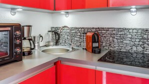 A compact kitchen with red cabinets, a coffee maker, a kettle, and a toaster. - Pegase Phenix by Interhome (Le Corbier)