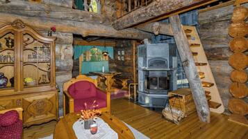 L’intérieur d’un chalet rustique, avec une table à manger en bois, un canapé, un buffet en bois et une cheminée en pierre.