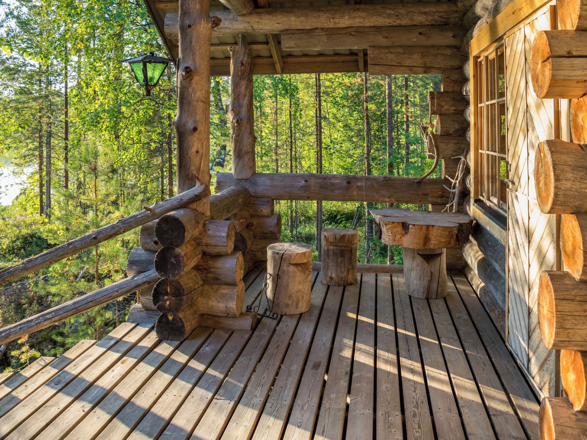 Eine Holzterrasse mit einer Bank und einem Tisch, umgeben von einem Wald.