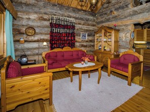 L'intérieur d'une cabane en rondins, avec un ensemble de canapés, un buffet en bois et une table à manger.
