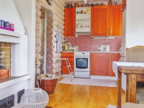 A compact kitchen with wooden cabinets, a stove, and a sink. - Käpälysmökki by Interhome (Nurmes)