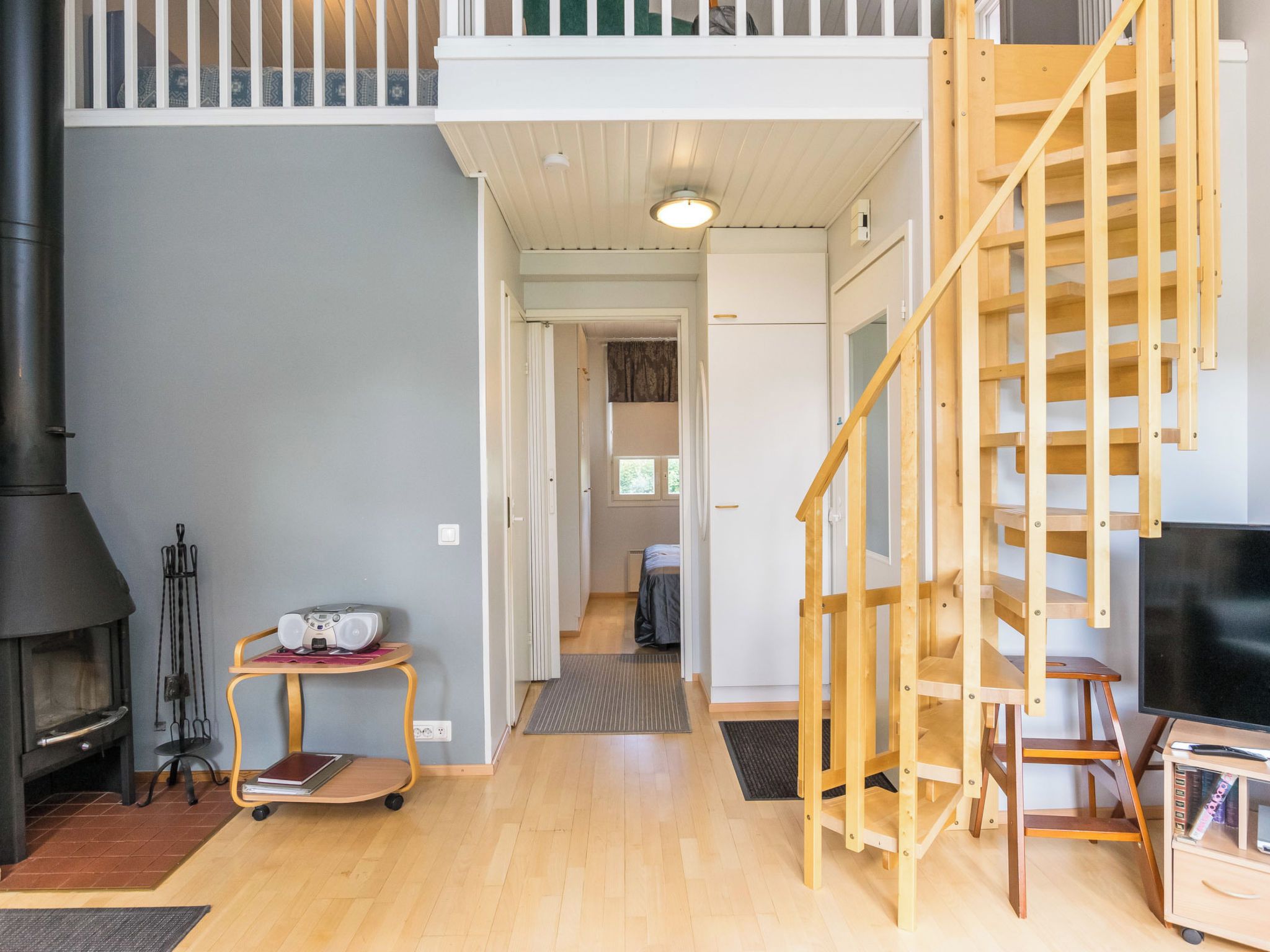 Un vaste espace de vie doté d’un haut plafond, d’une cheminée, d’un escalier en bois et d’un téléviseur.