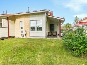Une maison de plain-pied avec un porche couvert, un petit patio et une pelouse bien entretenue.