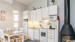 A modern kitchen with white cabinets, a built-in oven, a microwave, and a black wood-burning stove. - Prokatti by Interhome (Sotkamo)