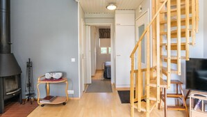 A spacious living area with a high ceiling, a wooden staircase, a fireplace, and a television. - Prokatti by Interhome (Sotkamo)