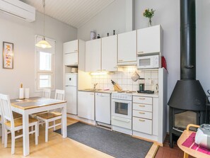A modern kitchen with white cabinets, a built-in oven, microwave, and a black wood-burning stove. - Prokatti by Interhome (Sotkamo)