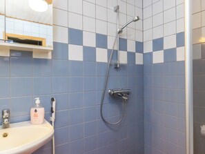 Une salle de bain avec une douche, un lavabo et une bouteille de shampoing.