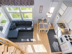 A compact living space with a sofa, dining table, kitchenette, and a view of the outdoors. - Prokatti by Interhome (Sotkamo)