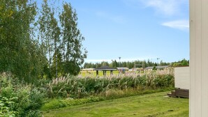 A grassy outdoor area with a bench, a gazebo, and a row of houses in the background. - Prokatti by Interhome (Sotkamo)